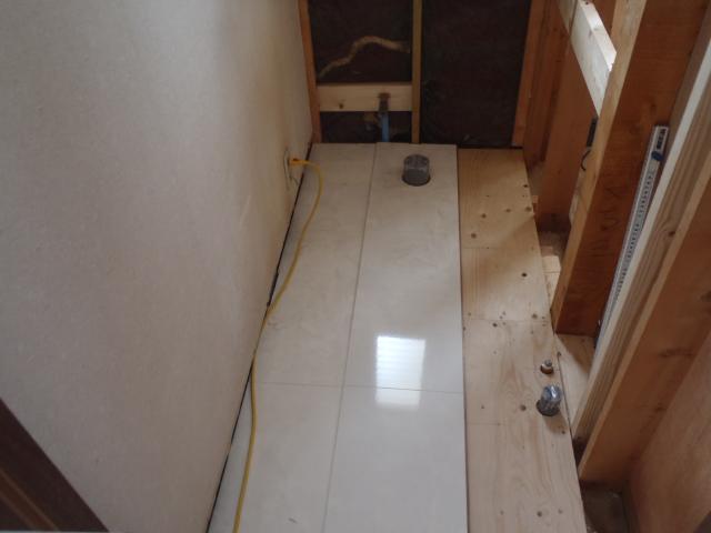床をすべて遣り替え、壁も壁面収納を設けるため解体して下地を作り替えていきます。<br />写真は床のフローリング施工中ですが、タイルのような鏡面仕上げの床材で高級感があります。