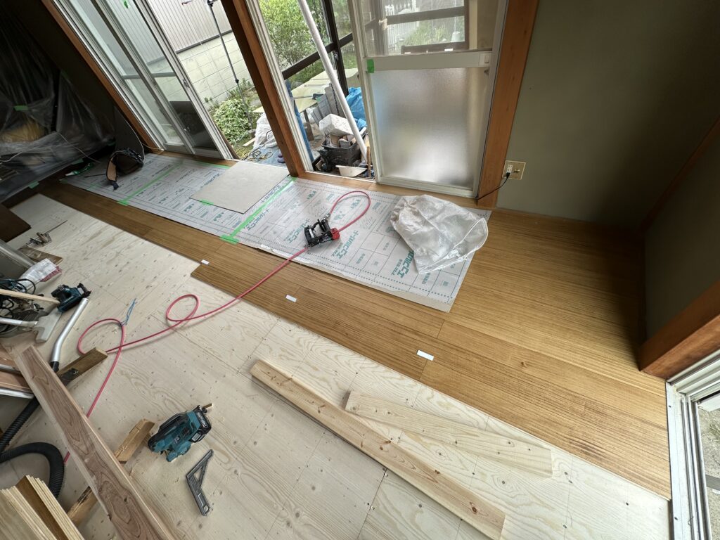 ご採用頂いたウッドワンの無垢フローリングピノアース（浮造り）を端から順番に張っていきます。張り終わったヶ所は養生材をしっかりと敷いて傷や汚れが付かない様にします。